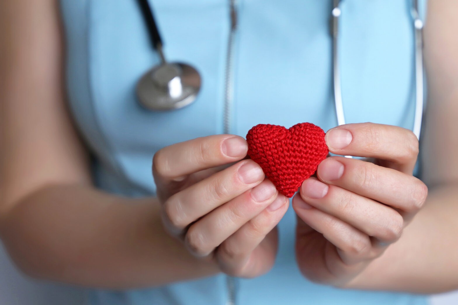 Cardiology and health care, woman doctor holding red knitted heart in hands